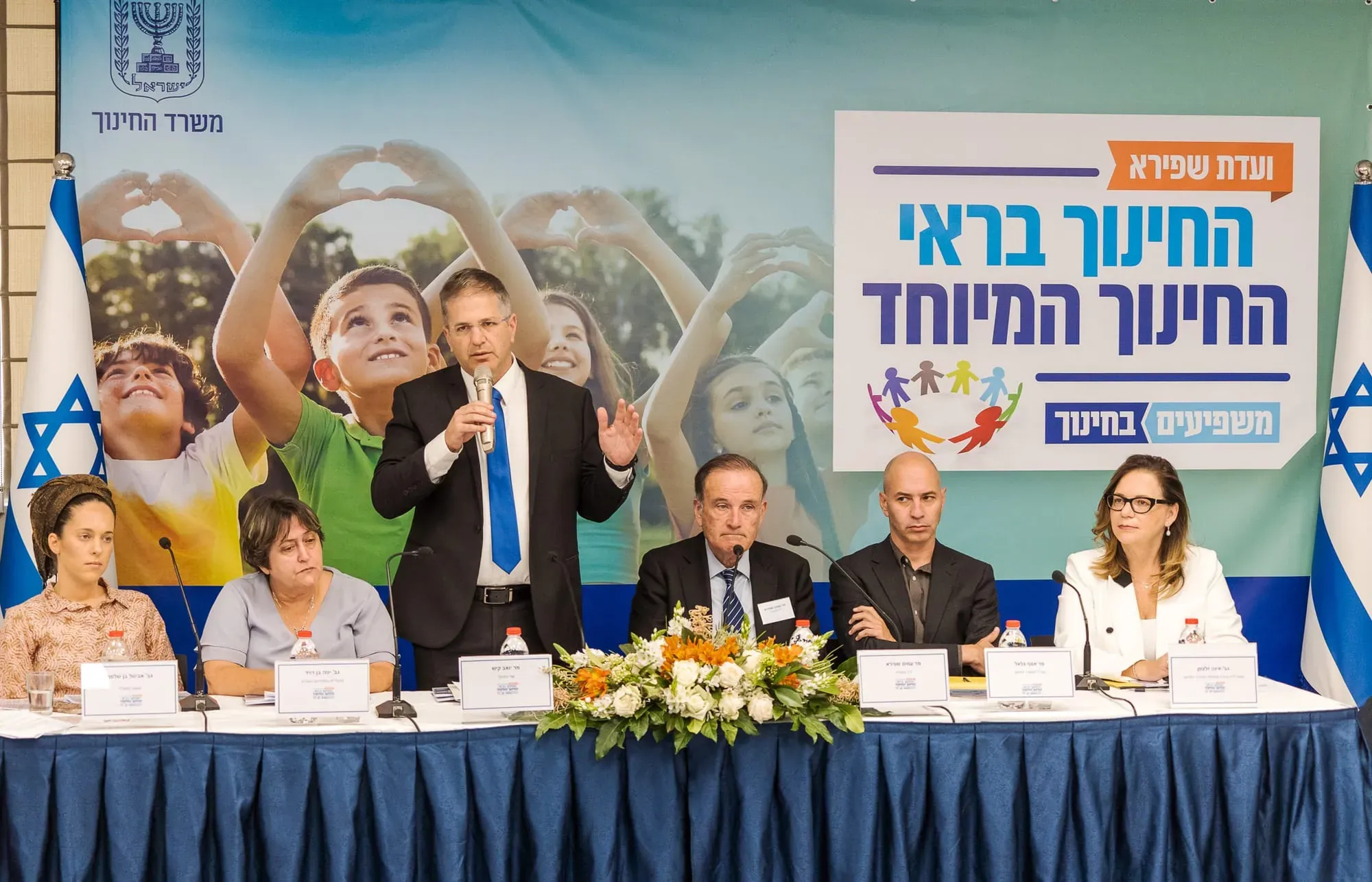 שולחן ראשי בכנס על חינוך בריאותי עם זר פרחים וצוות מרצים
