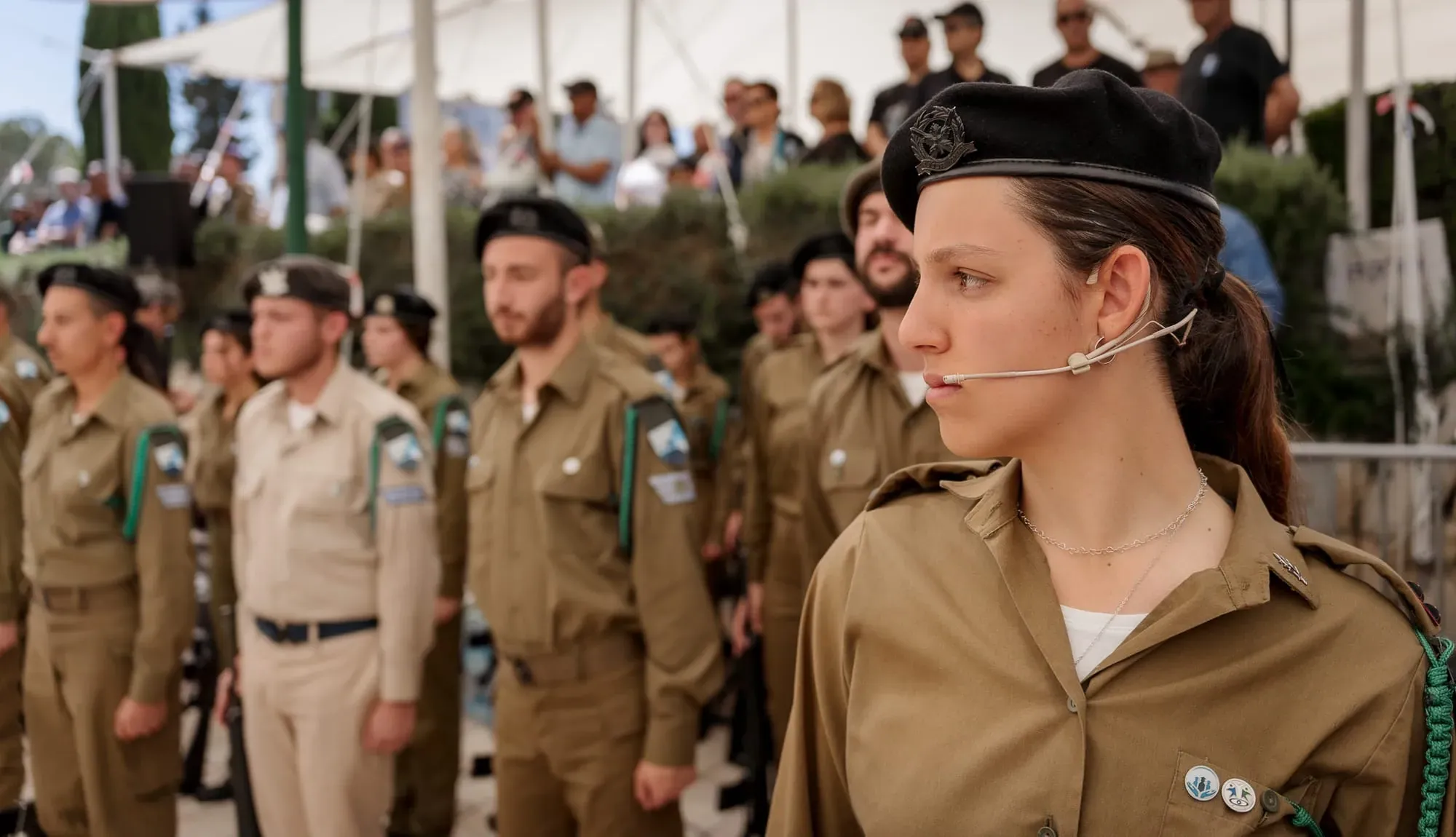 חיילת במדים ובכומתה עם אוזניית מיקרופון בטקס צבאי
