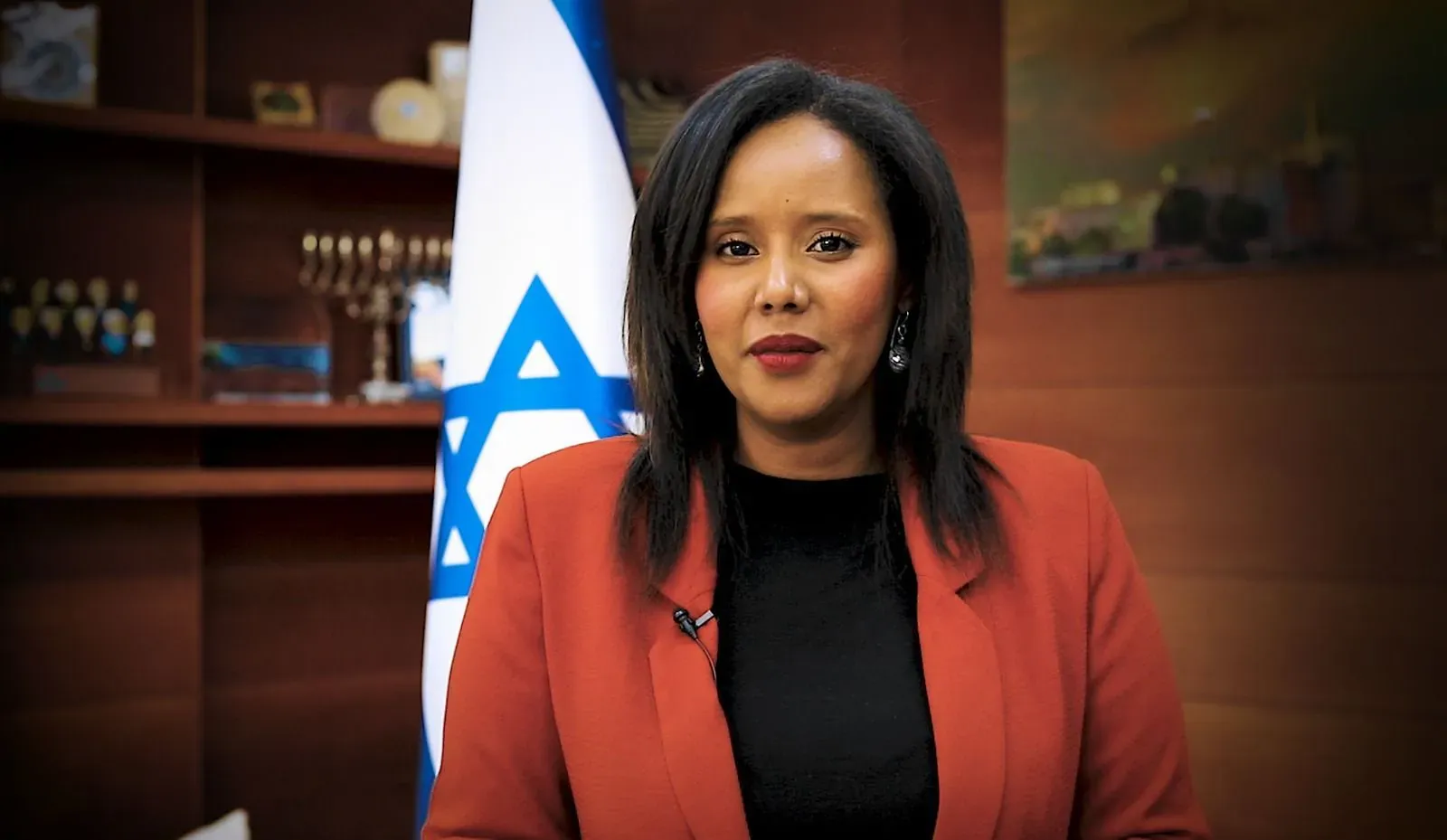 צילום תדמית: פנינה תמנו שטה בז'קט כתום לצד דגל ישראל