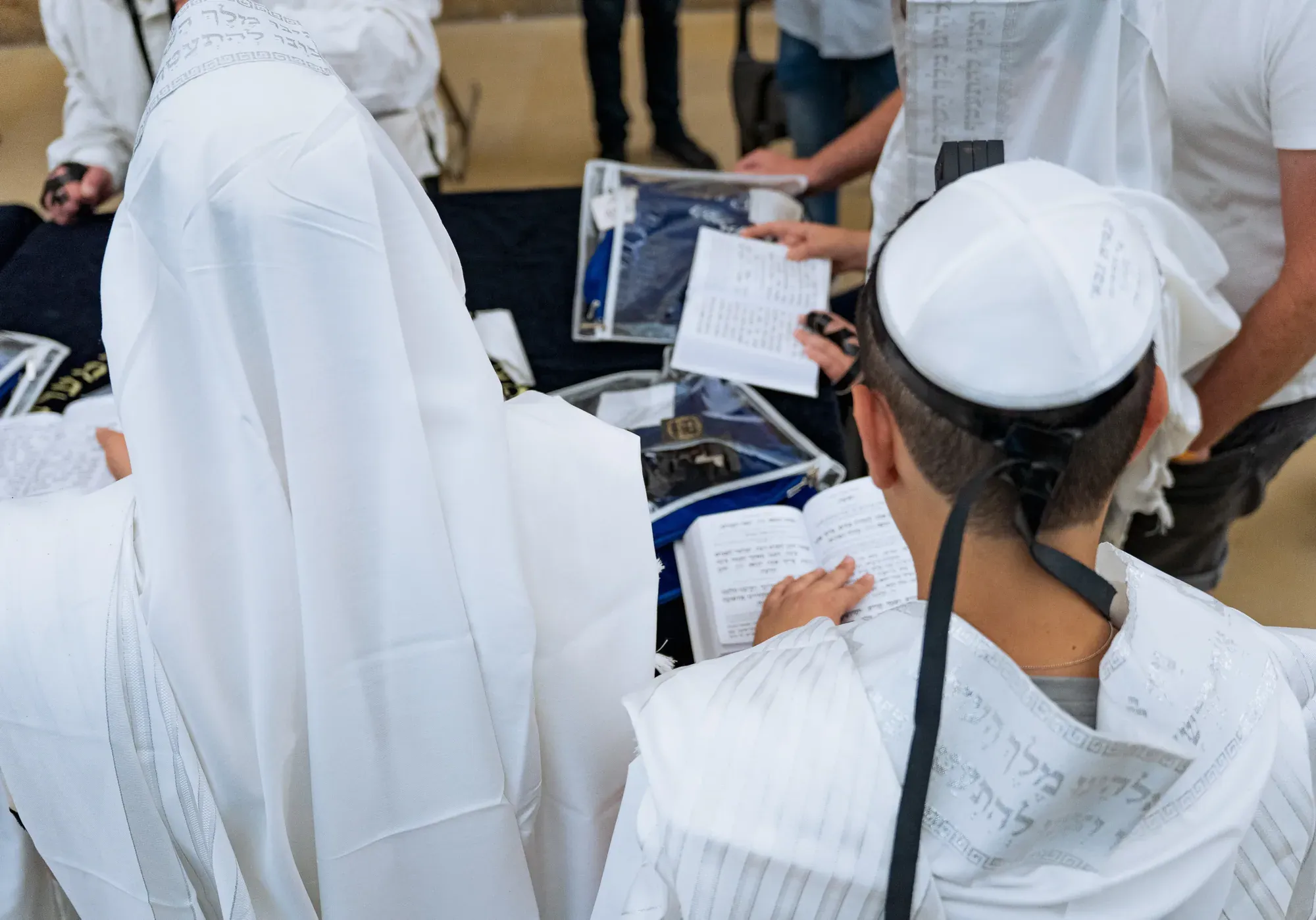 קהל מתפלל בלבוש לבן עם ספרים ביד