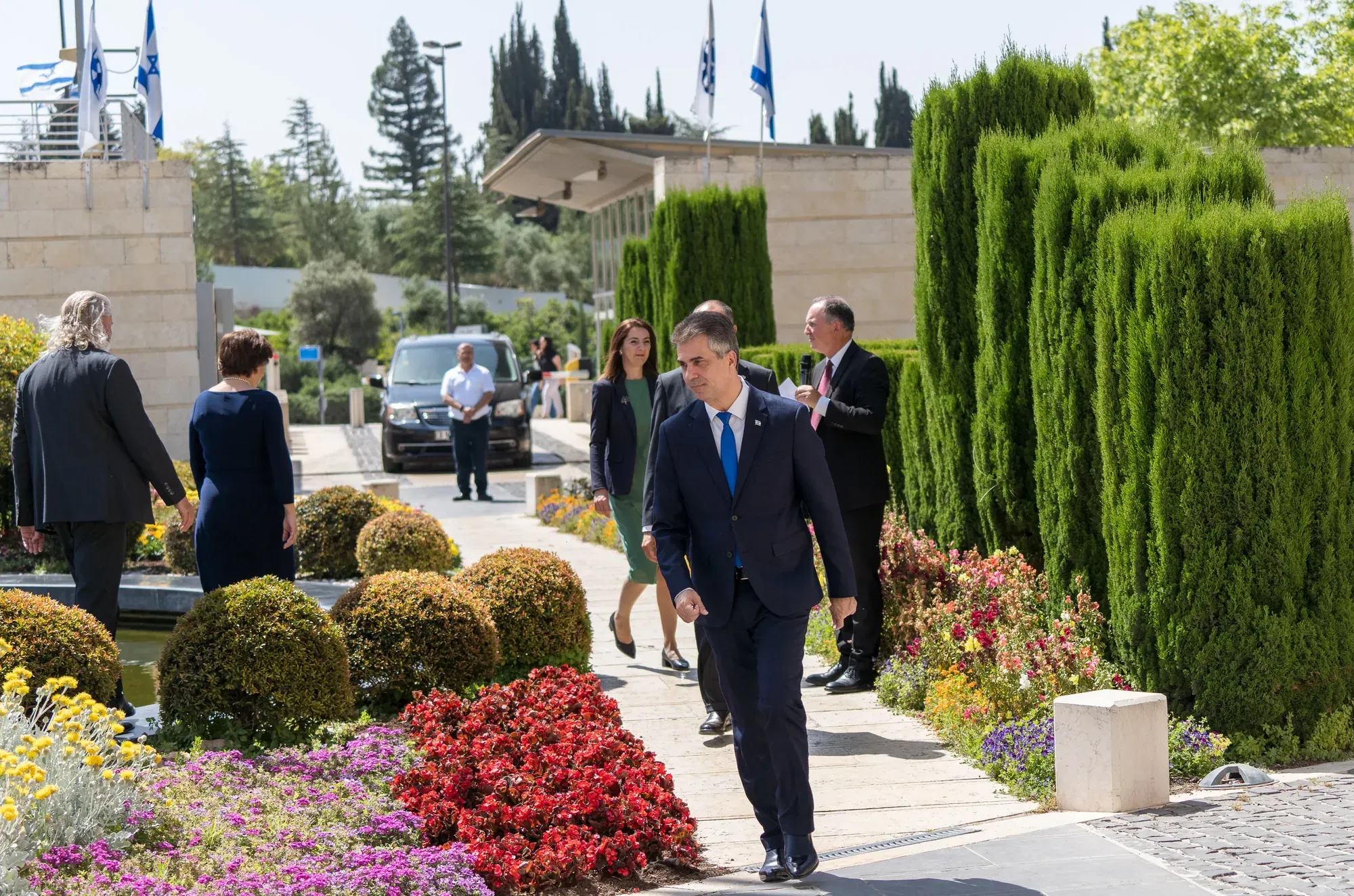 שני אנשים צועדים בשביל גינה מטופח ליד בניין ממשלתי