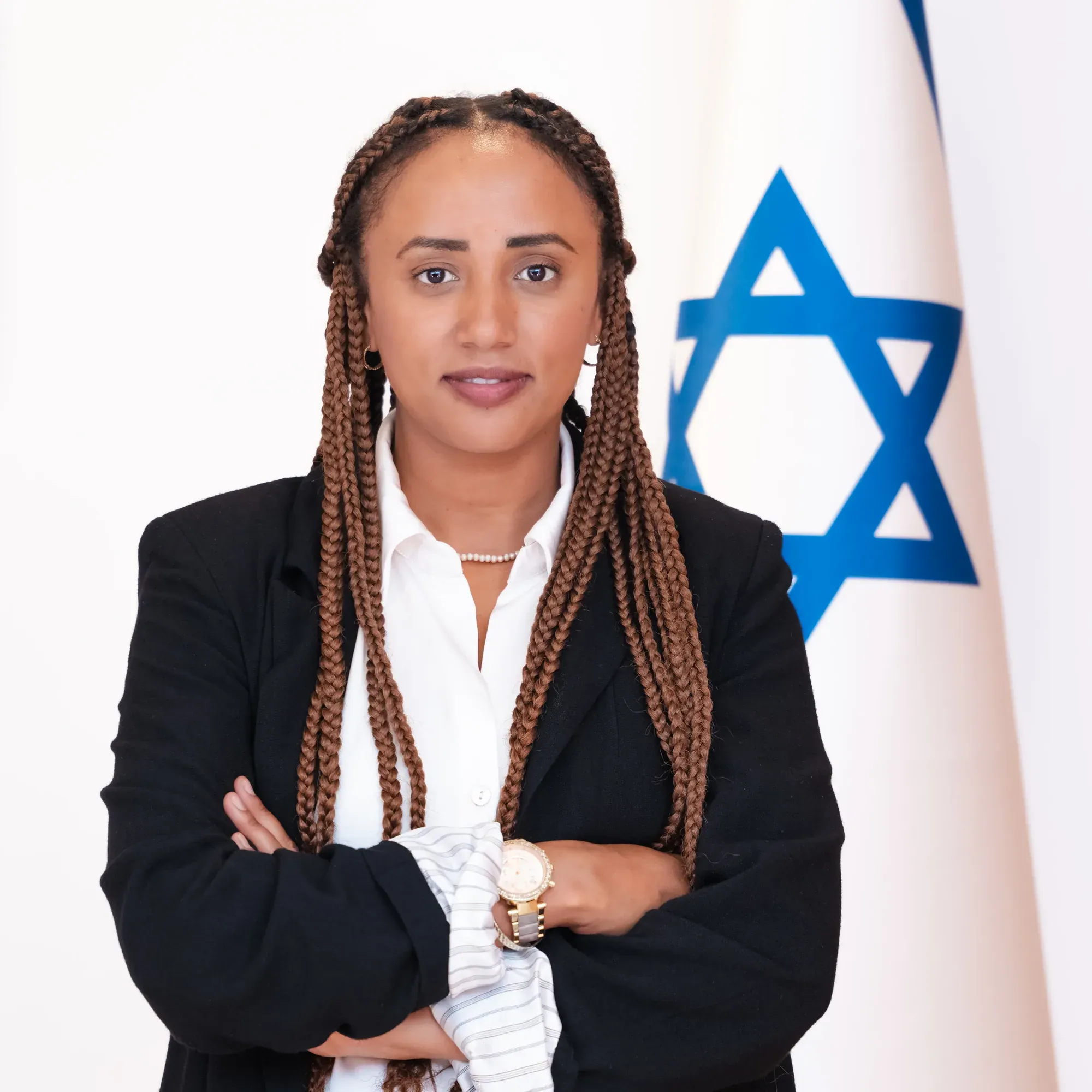 צילום תדמית: אישה בחליפה שחורה וידיים שלובות ליד דגל ישראל