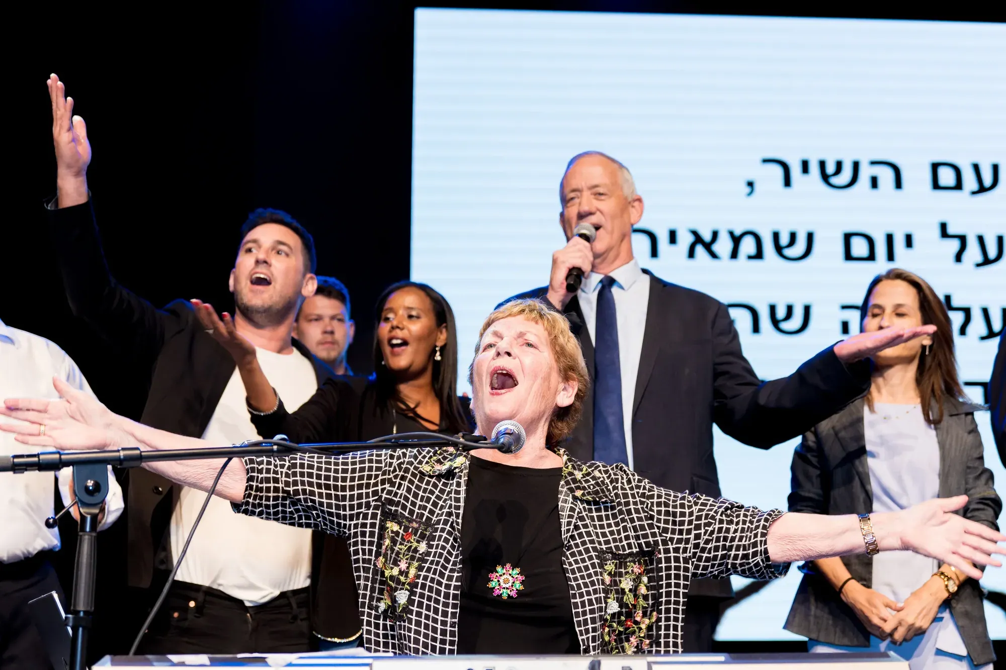 אנשים שרים ומנופפים על במה בסיום כנס