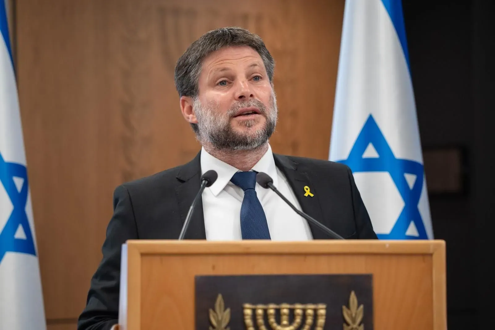 צילום אירוע: בצלאל סמוטריץ' בכנס ליד דוכן עם סמל המדינה