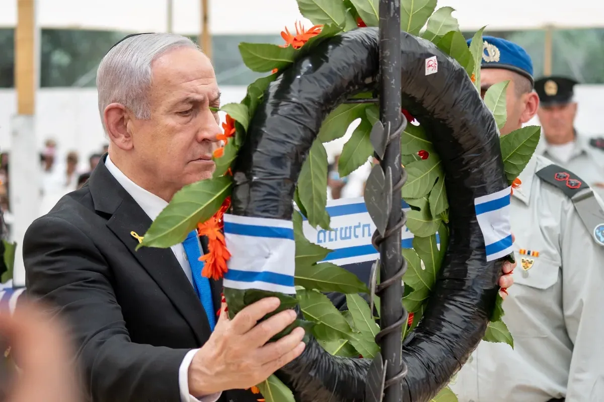 אדם מניח זר פרחים בטקס רשמי, ברקע חיילים ומשתתפים