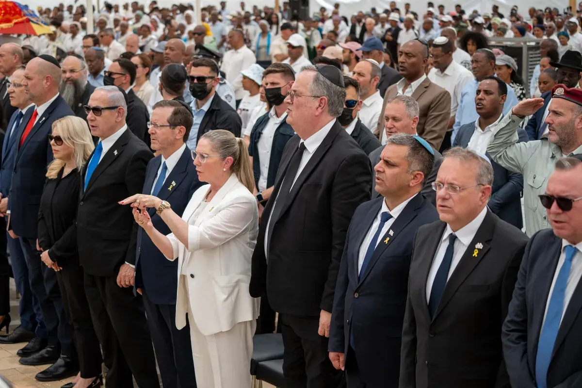 קהל רב בטקס ממלכתי תחת כיפת שמיים, אנשים עומדים בצורה חגיגית