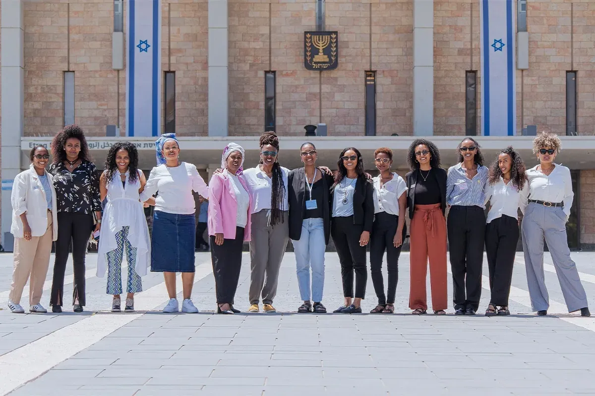 תמונה קבוצתית של נשים בשורה מול בניין הכנסת