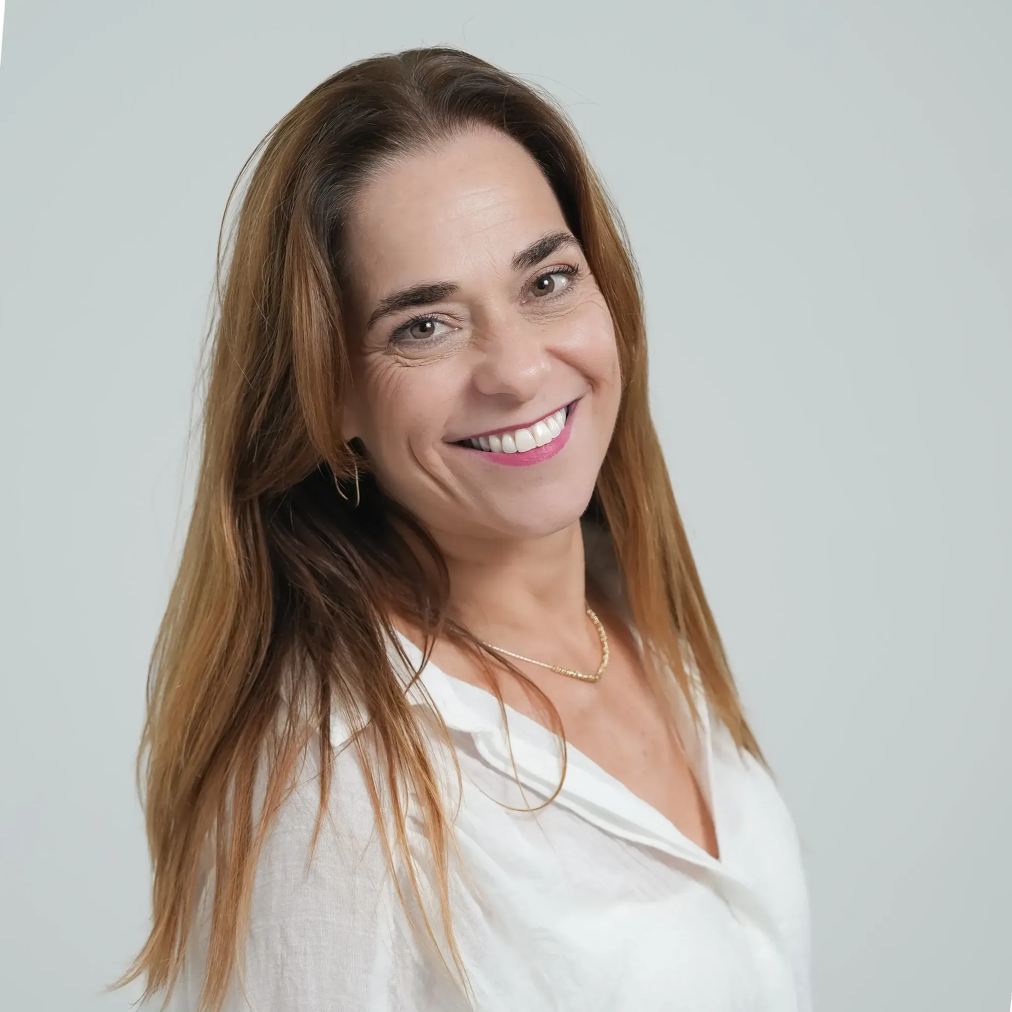 צילום תדמית: פורטרט נשי מחויך בחולצה לבנה על רקע בהיר