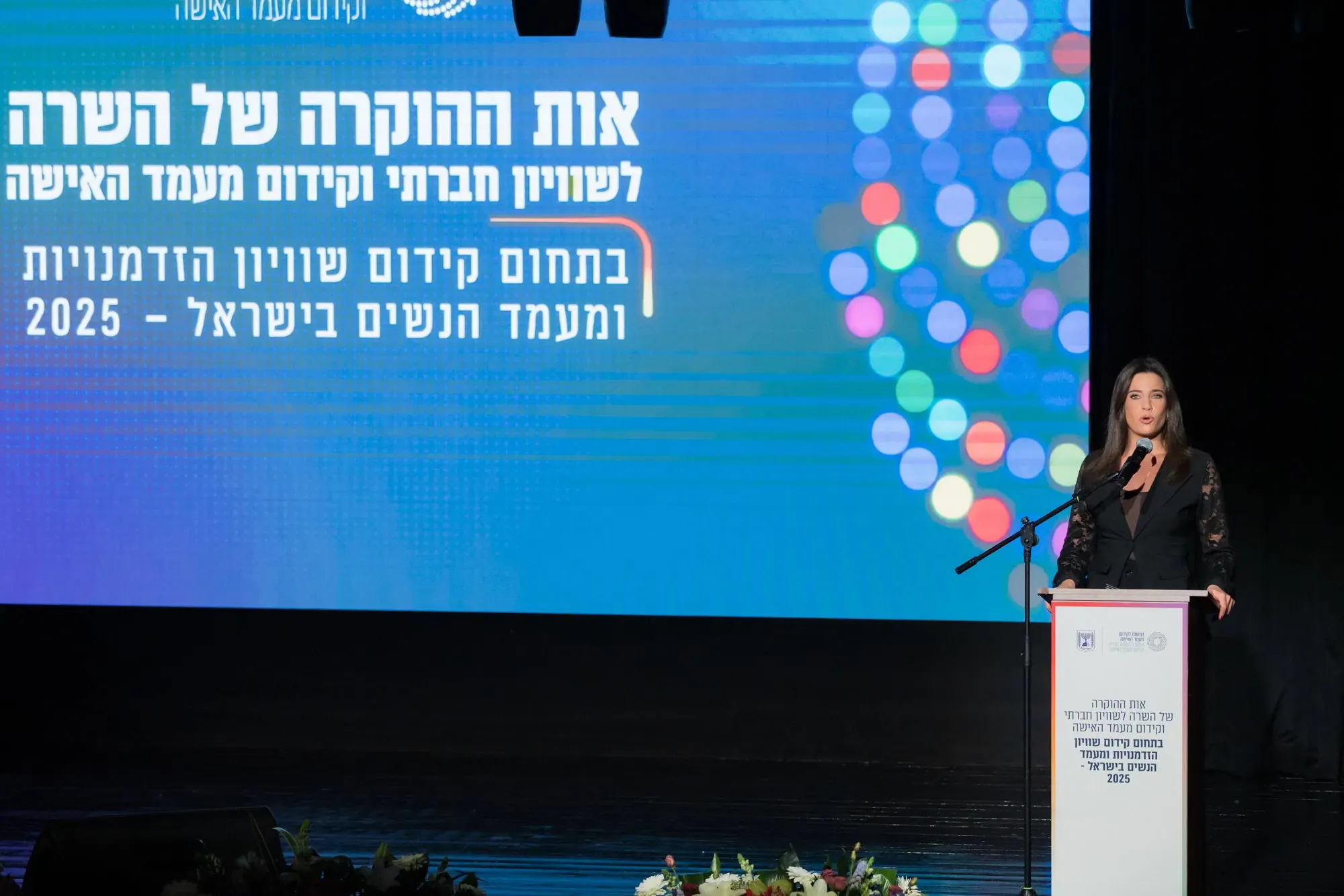 אשה נואמת על במה בכנס לקידום שוויון הזדמנויות ומעמד נשים בישראל